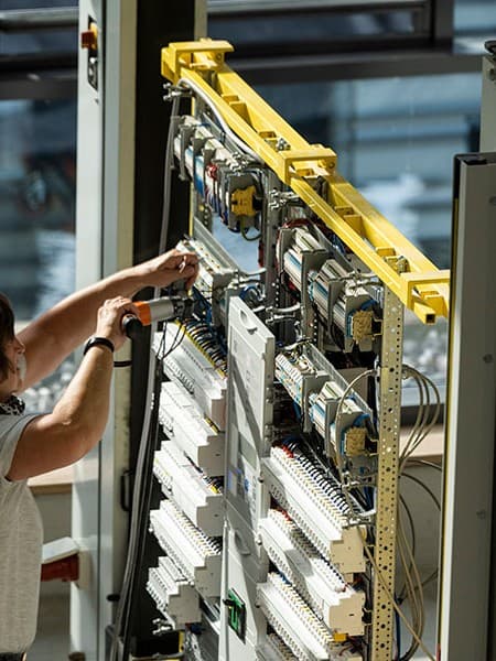 Geöffnete Elektroverteilung, Monteur prüft die Module vor der Auslieferung