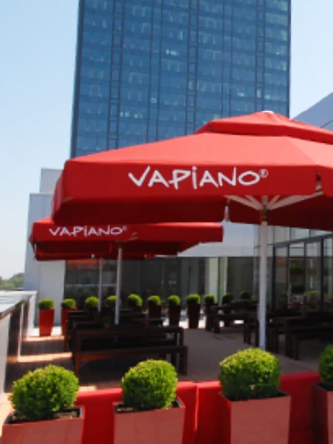Vapiano-Restaurant mit Terrasse und roten Sonnenschirmen