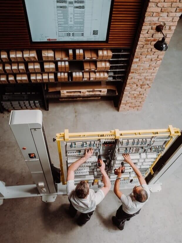 Two technicians assembling an electrical distribution board tailored to the store